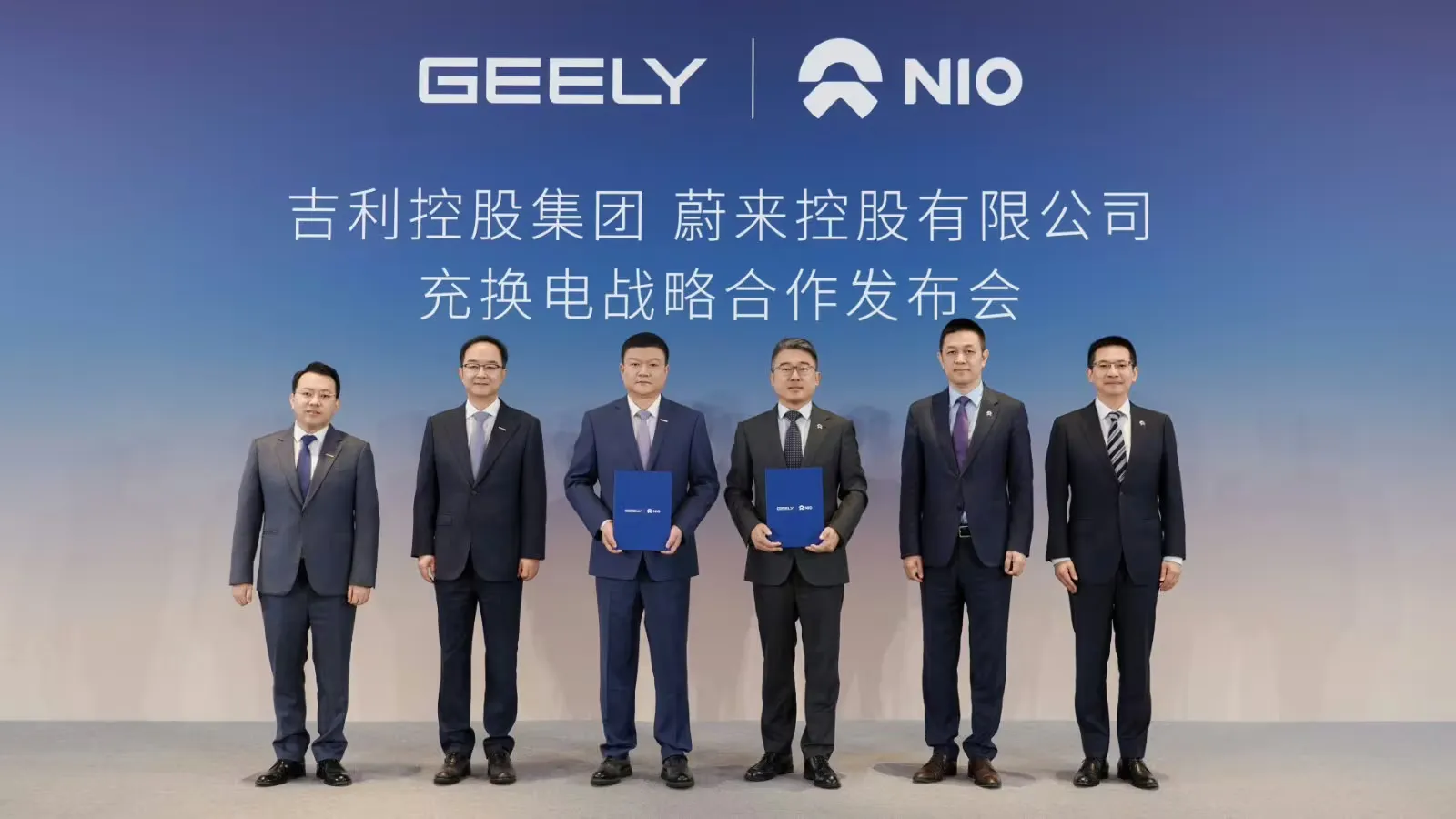 Representantes da Geely e da Nio posam com pastas do acordo durante uma cerimônia de assinatura para sua parceria em carregamento e troca de baterias.