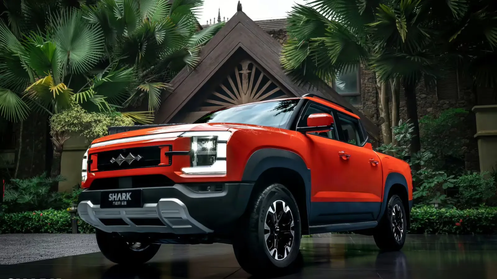 Pick-up híbrida plug-in laranja da BYD Shark com emblema Fang Cheng Bao, vista de três quartos pela frente em meio a vegetação tropical.