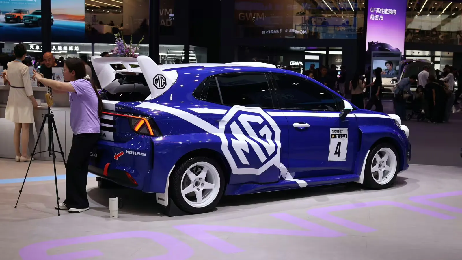 Hatchback azul da MG com gráficos esportivos brancos, rodas brancas e uma grande asa traseira em exibição na Feira Automobilística de Pequim em abril de 2026.