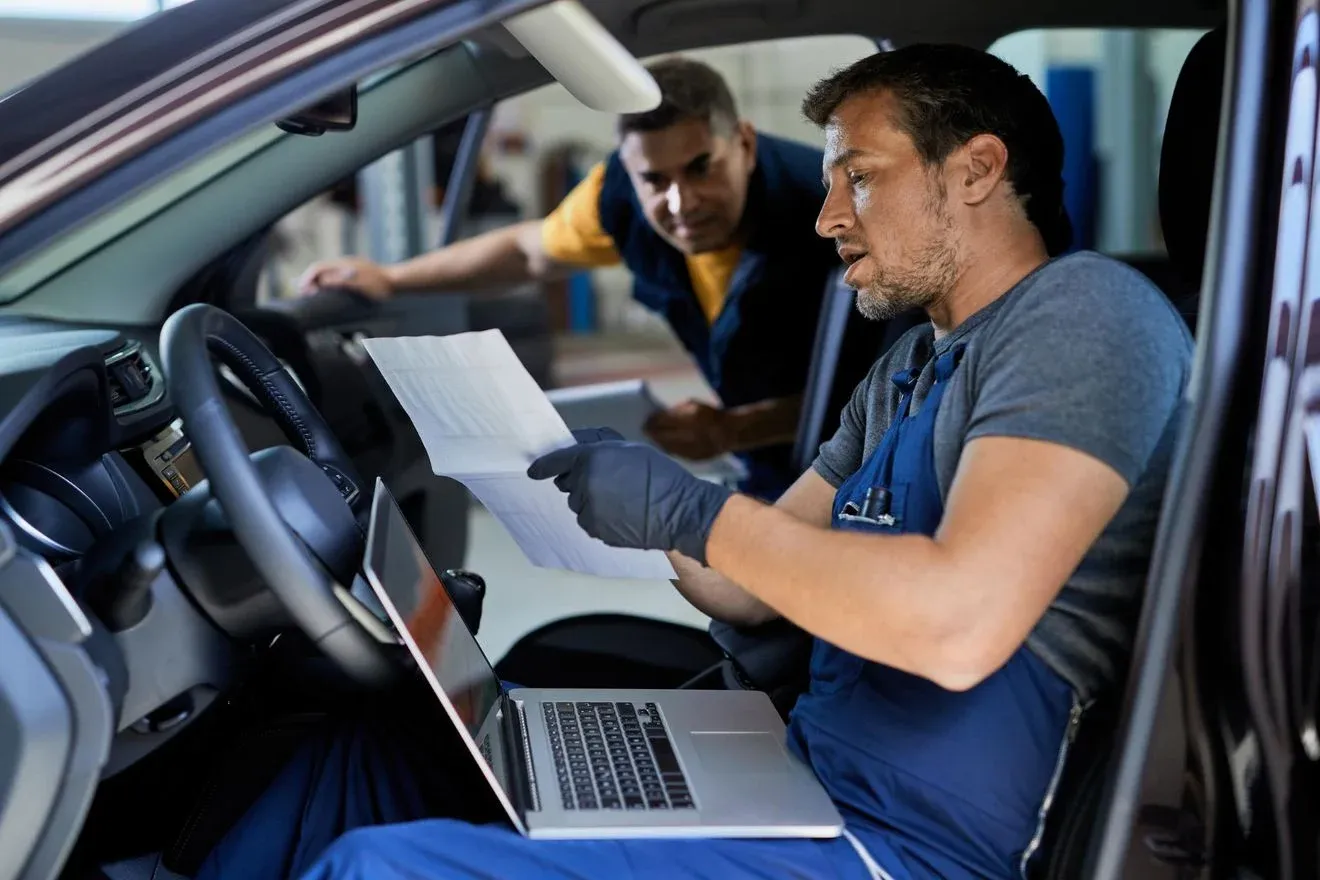 reparador-automoviles-hablando-su-colega-mientras-realiza-diagnosticos-automoviles-analiza-datos-taller