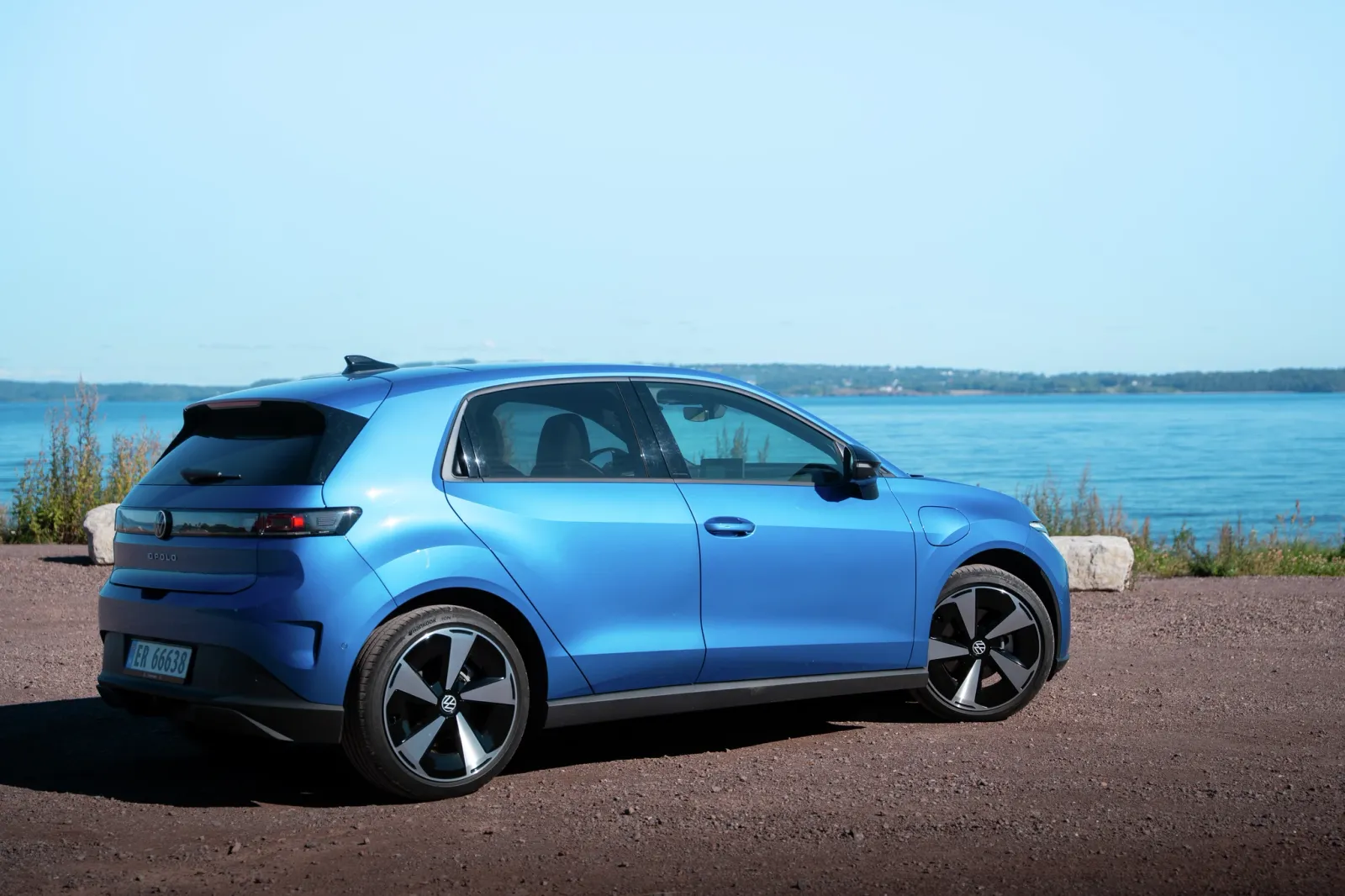 Um Volkswagen ID.2 elétrico de estilo perua estacionado perto de uma bela orla portuária em um dia ensolarado.