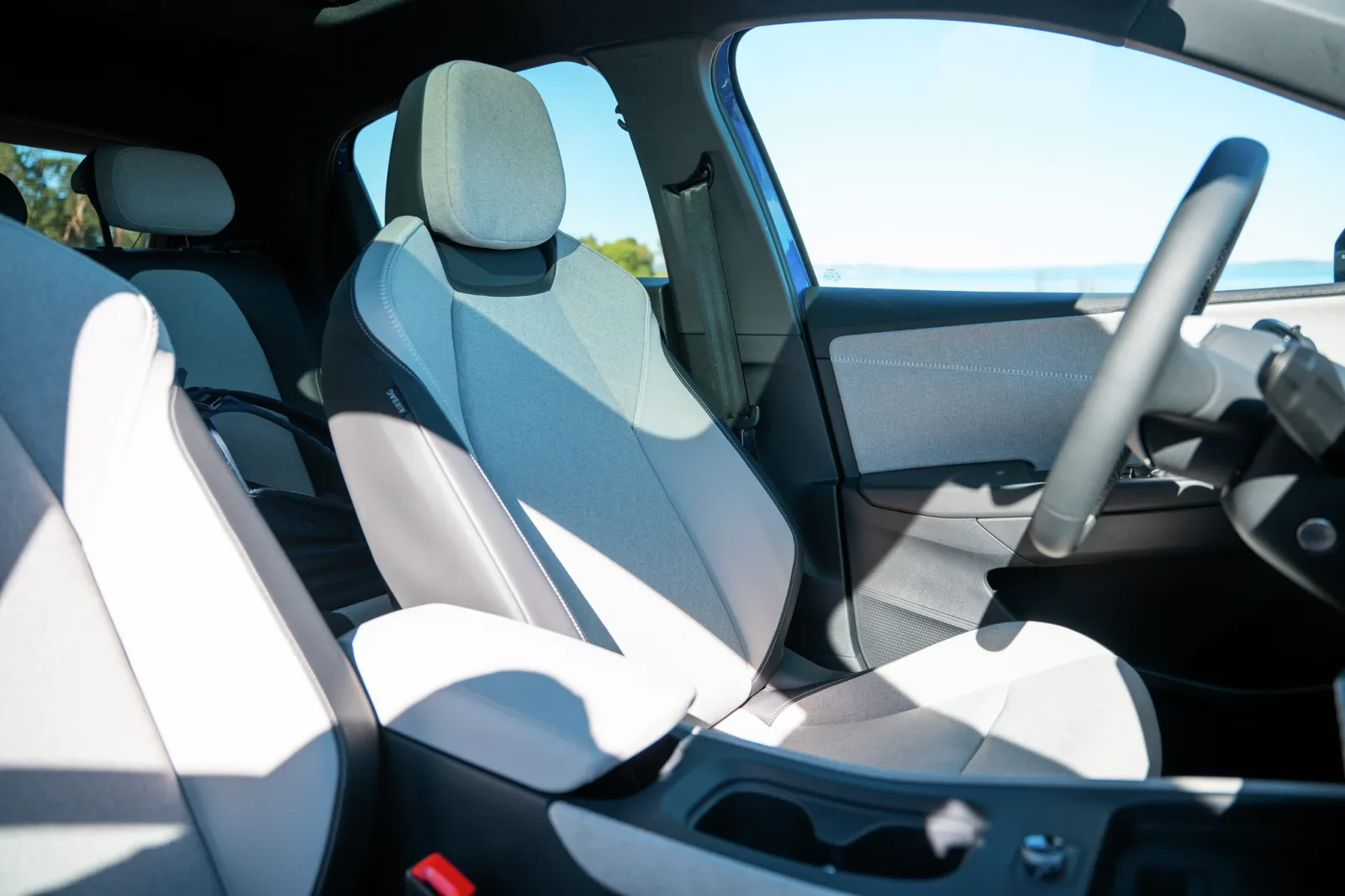 Visão interna de um carro elétrico BMW i3, mostrando os encostos e o volante revestidos em couro branco.