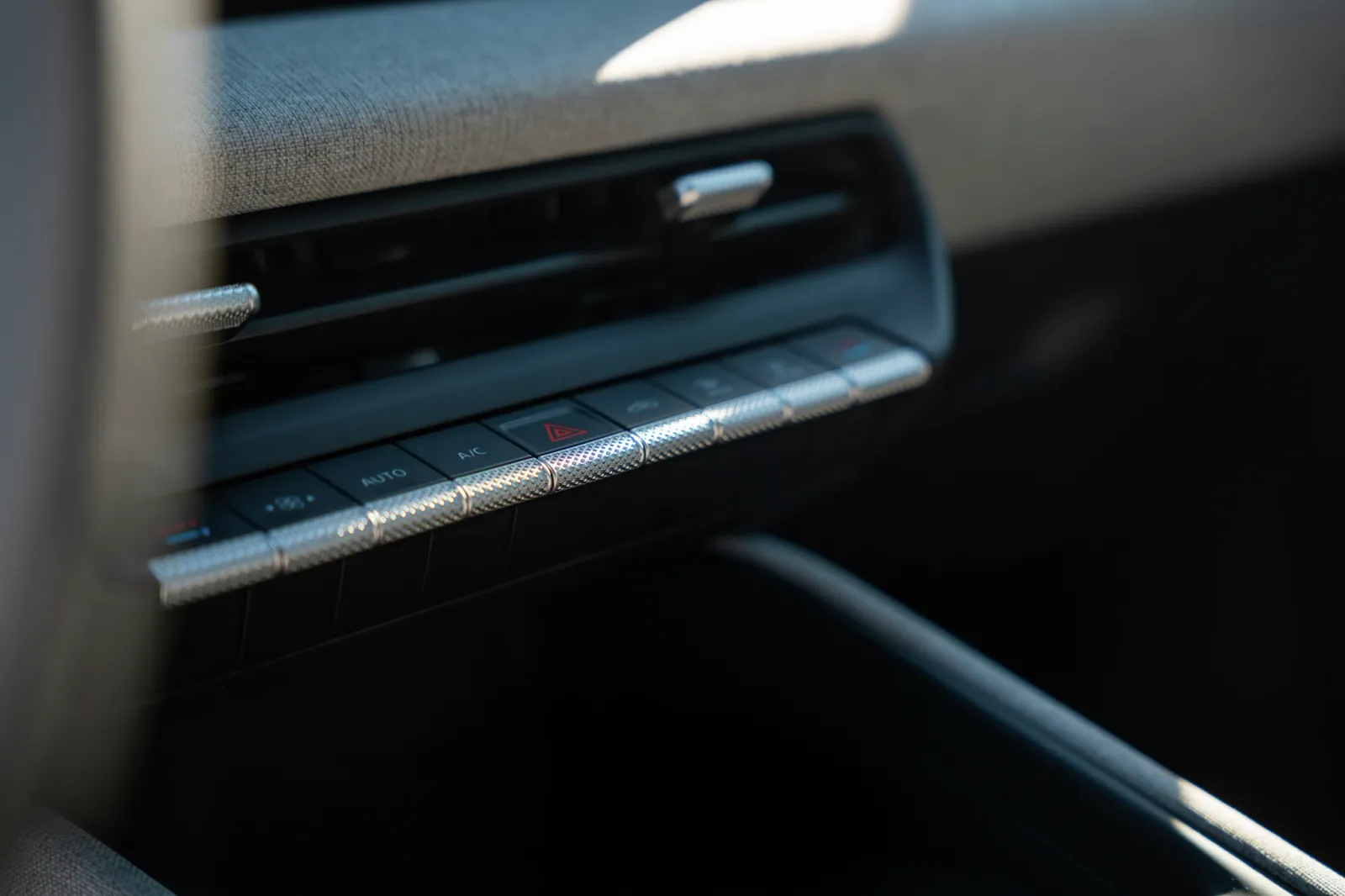 Foto de close do sistema de ar-condicionado no painel do carro, com opção AUTO, botões de controle e indicadores luminosos, além de detalhes cromados.