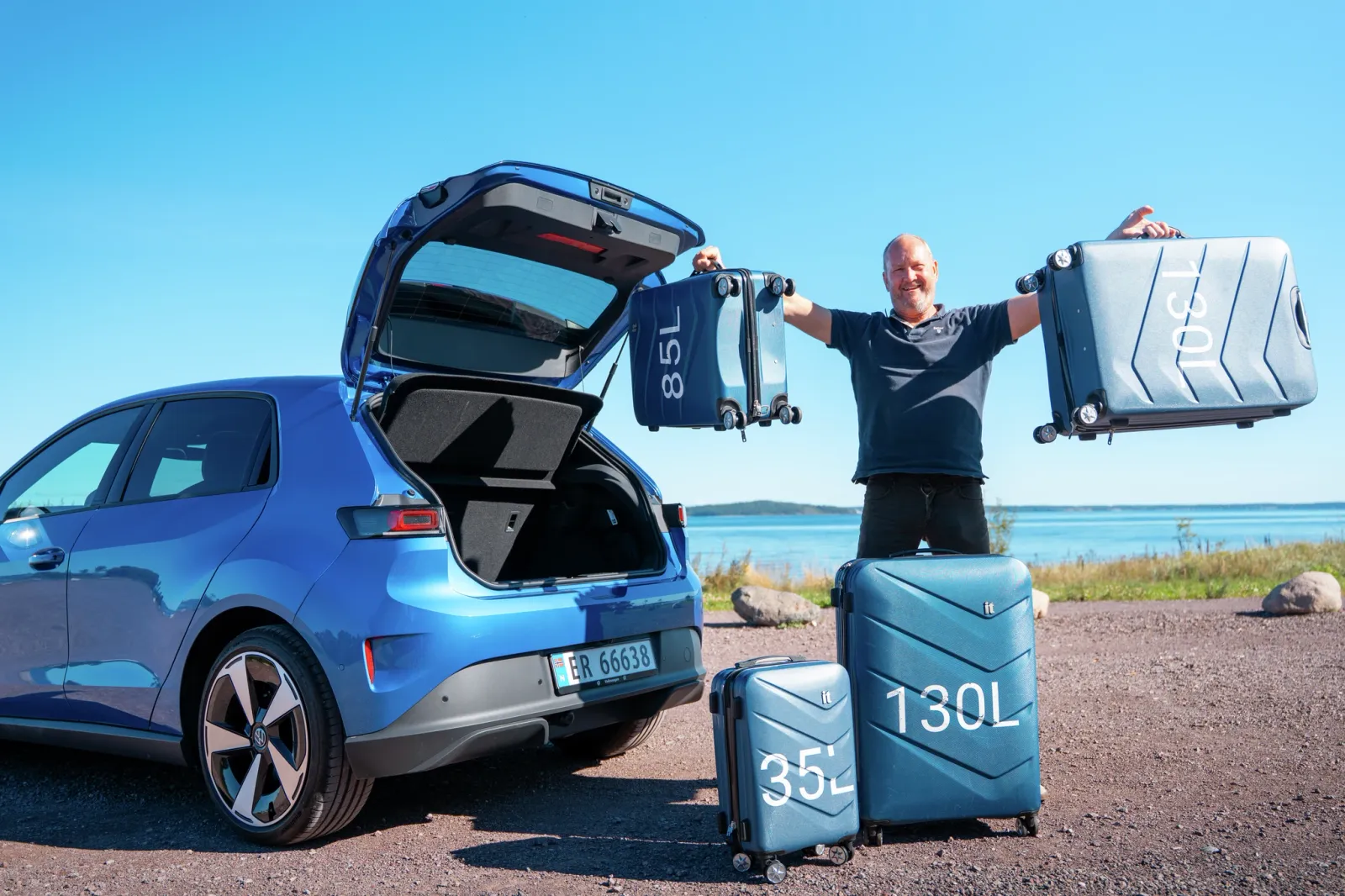 Homem segurando malas de 85 litros e 190 litros ao lado de um compartimento de bagagem azul aberto em um carro elétrico, com 35 litros e 130 litros de bagagem na parte traseira.