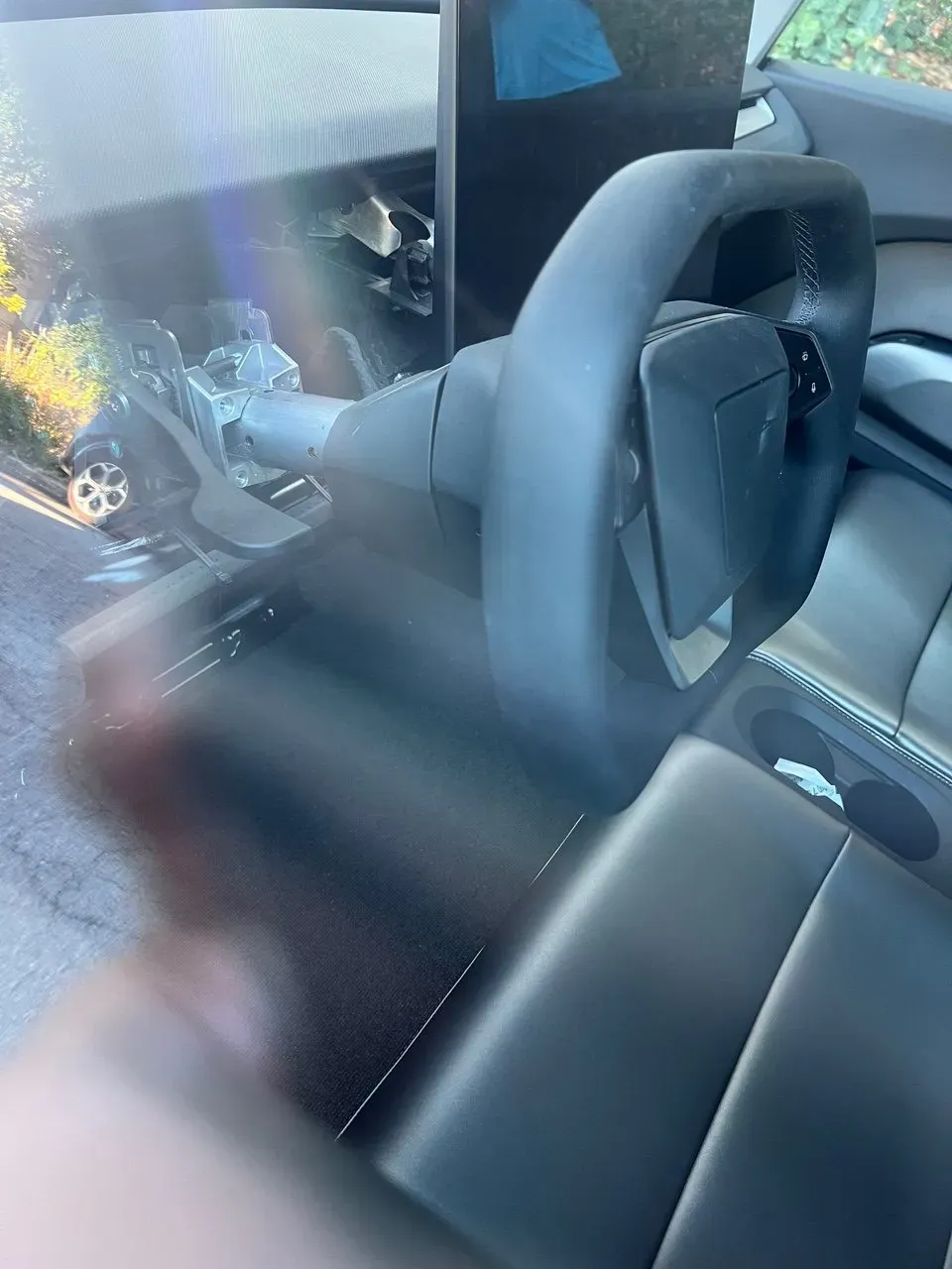Squared-off Cybertruck steering wheel mounted on an exposed column in a Tesla Cybercab