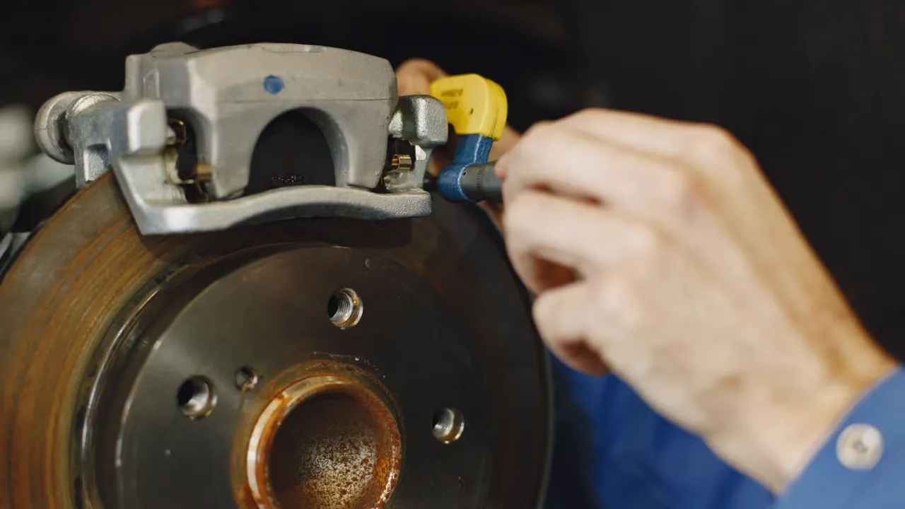 Mecânico medindo a espessura de um disco de freio com um paquímetro