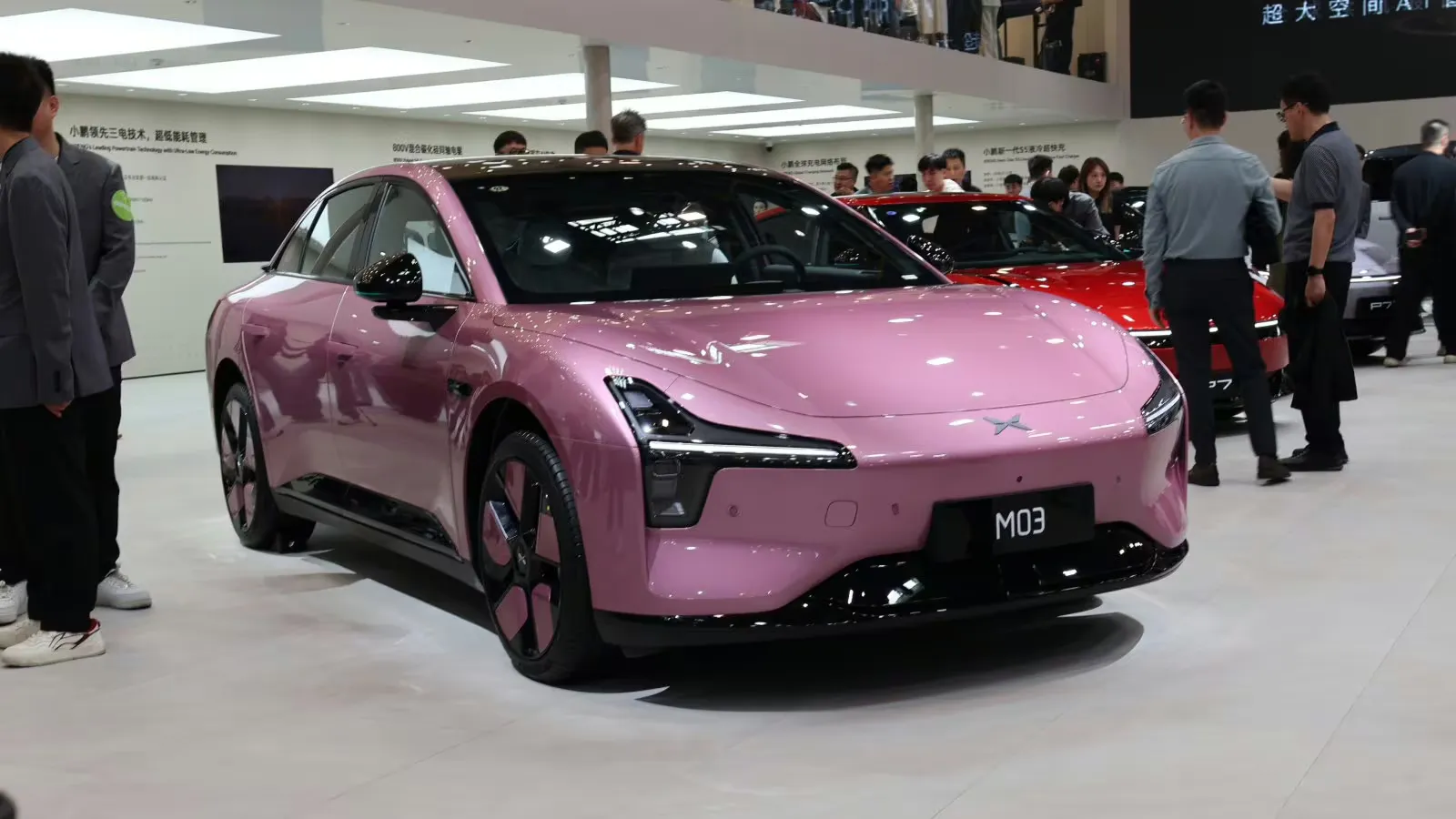 Sedã elétrico rosa Xpeng Mona M03 em exibição na Feira Automotiva de Pequim em abril de 2026, visto do ângulo traseiro superior esquerdo.