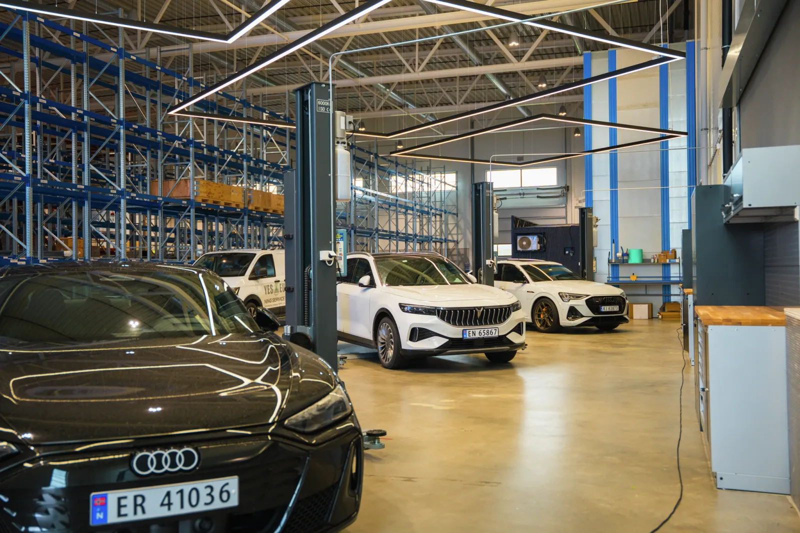 Interior of a car dealer exhibition space with several vehicles on display, including an Audi and white cars.