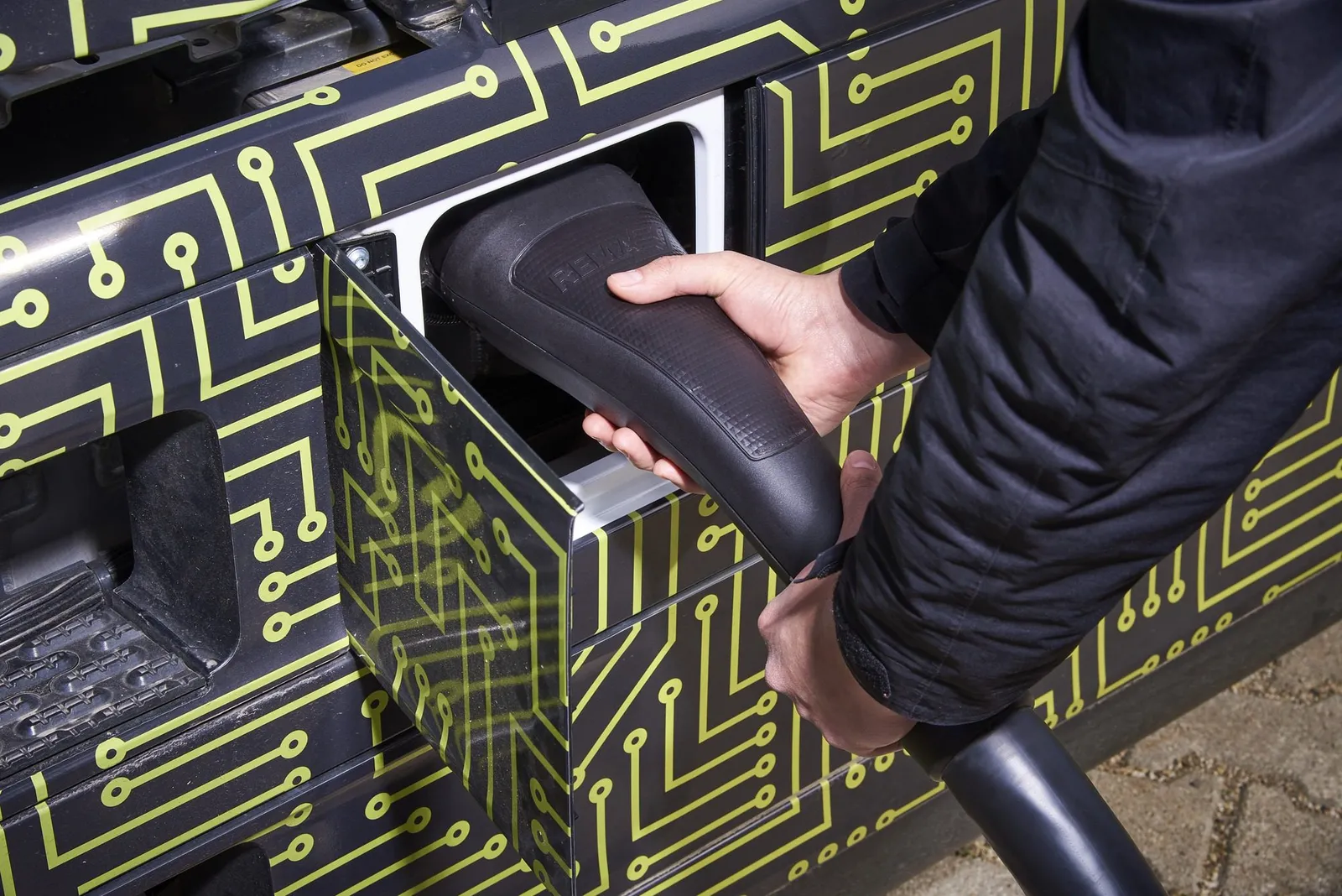 A technician plugs an MCS charging connector into a Mercedes-Benz test truck.