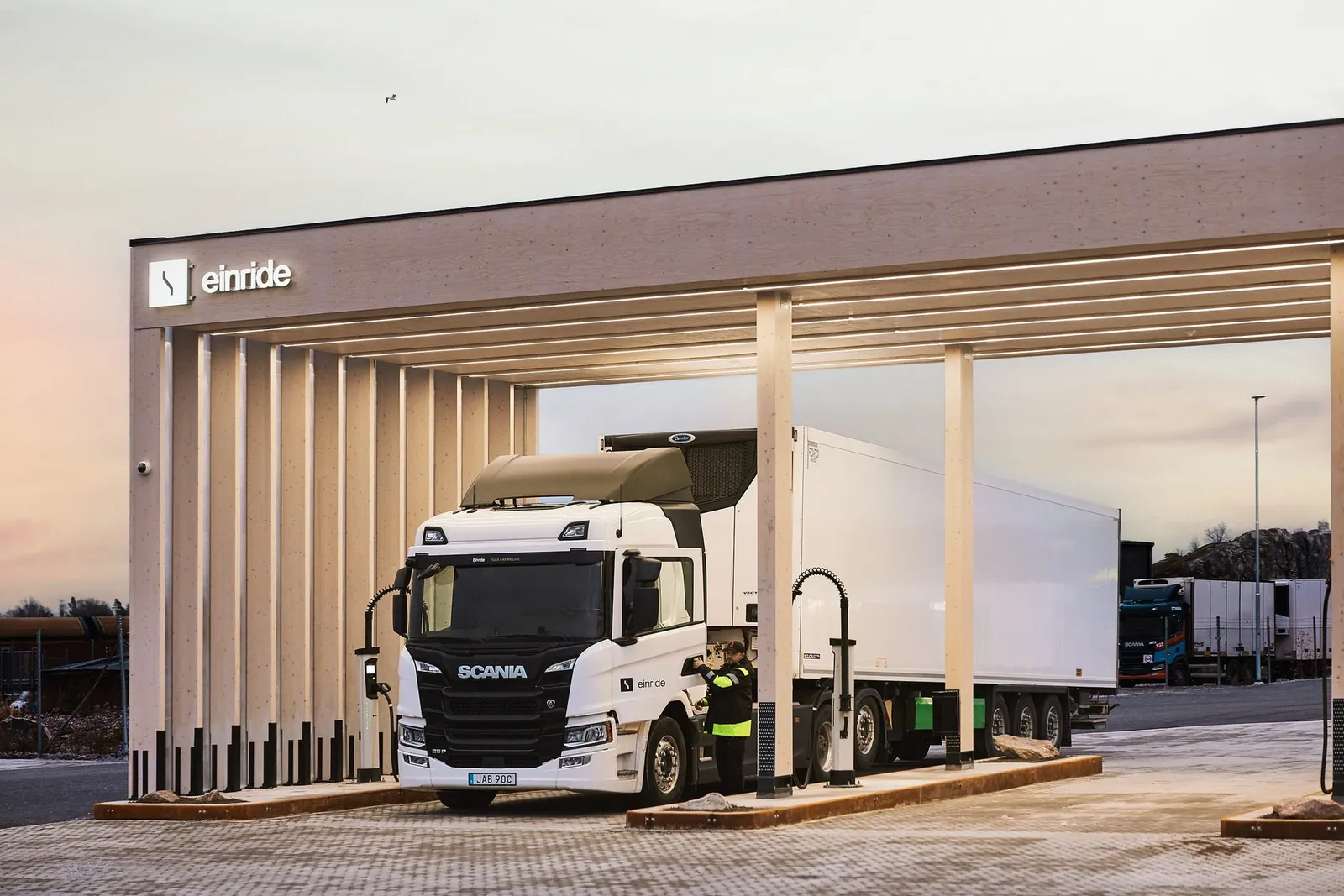 An Einride Scania electric truck charging beneath a timber canopy.